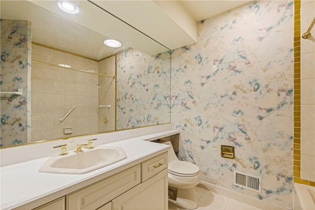 bathroom featuring toilet, vanity, tiled shower, and tile patterned floors