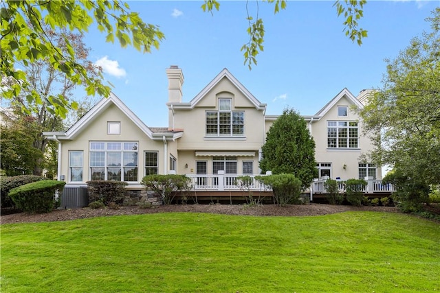 rear view of property featuring a lawn, a wooden deck, and central air condition unit