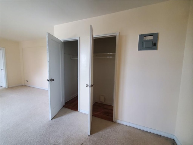 unfurnished bedroom with light carpet, electric panel, and a closet