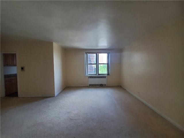 unfurnished room with light colored carpet and radiator heating unit