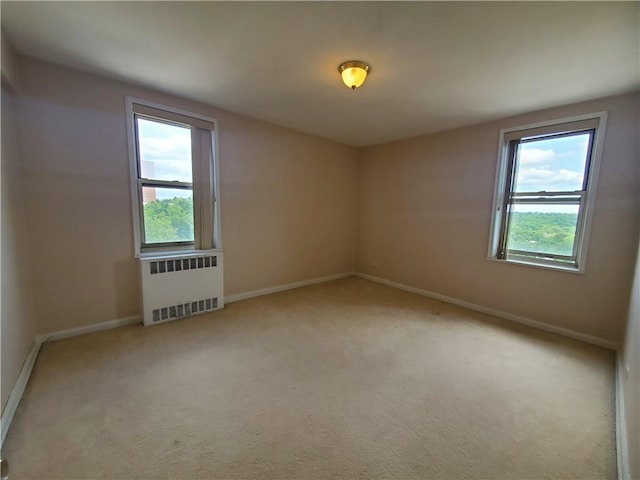 spare room featuring radiator heating unit and light colored carpet