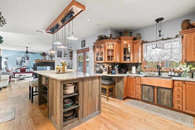 kitchen with ceiling fan, a breakfast bar, pendant lighting, and light wood-type flooring