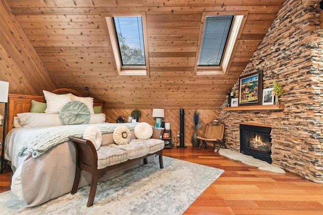 living area featuring vaulted ceiling with skylight, wood walls, light wood-type flooring, and a fireplace