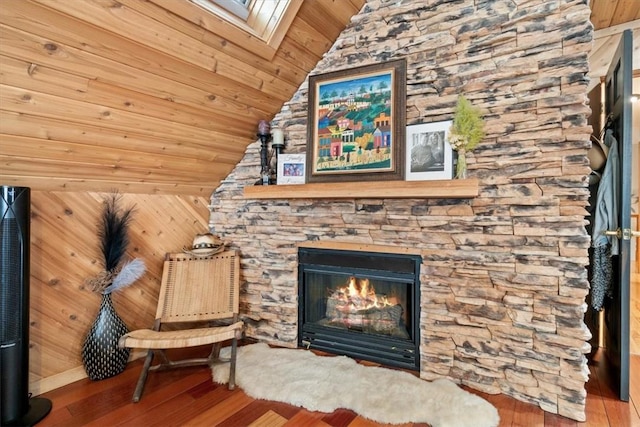 unfurnished room featuring wood ceiling, vaulted ceiling, wooden walls, wood-type flooring, and a fireplace