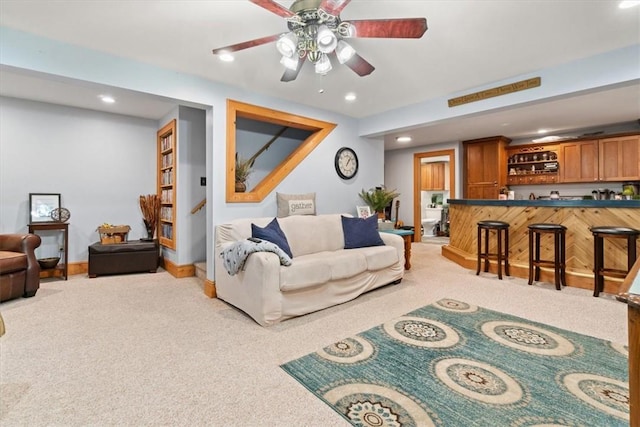 carpeted living room featuring bar area and ceiling fan