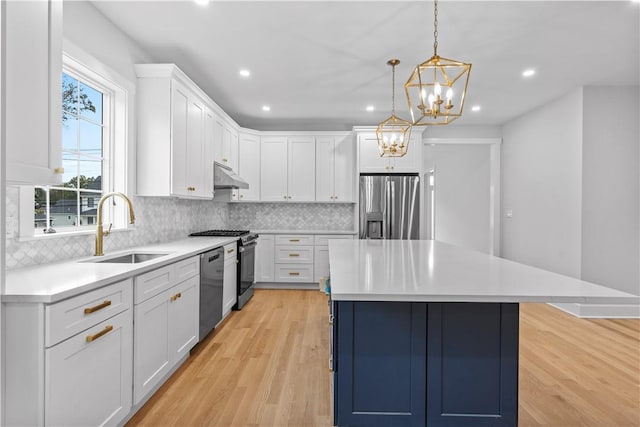 kitchen featuring white cabinets, hanging light fixtures, sink, appliances with stainless steel finishes, and light hardwood / wood-style floors