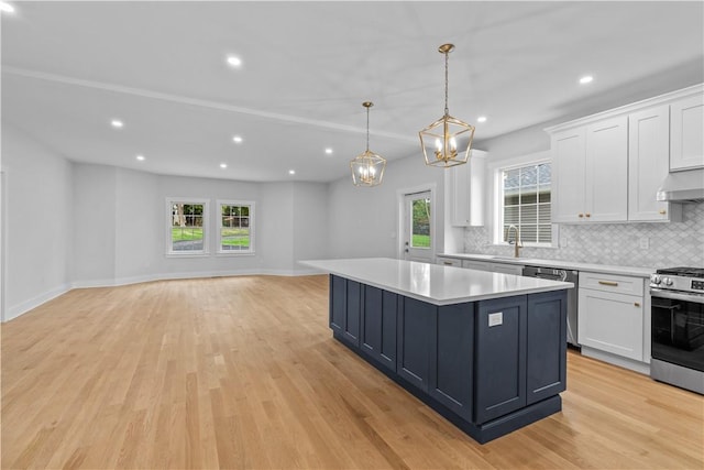 kitchen featuring pendant lighting, stainless steel appliances, white cabinetry, and light hardwood / wood-style flooring