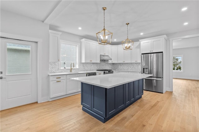 kitchen with white cabinets, pendant lighting, a kitchen island, and appliances with stainless steel finishes