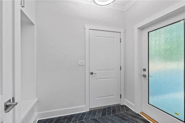 entryway featuring dark tile patterned floors and crown molding