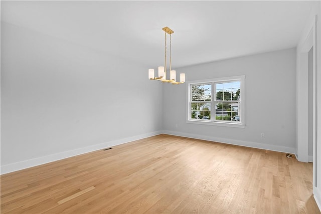 unfurnished room featuring light hardwood / wood-style floors and an inviting chandelier