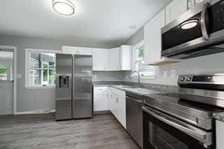 kitchen with stainless steel appliances, white cabinetry, a wealth of natural light, and light hardwood / wood-style flooring