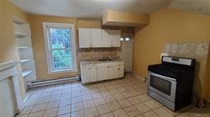 kitchen featuring stainless steel range, sink, light tile patterned floors, baseboard heating, and white cabinets