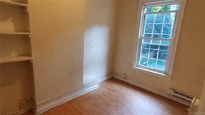 unfurnished room featuring baseboard heating, a wealth of natural light, and light hardwood / wood-style flooring