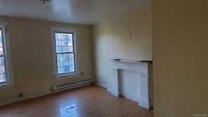 unfurnished room with baseboard heating and light hardwood / wood-style floors