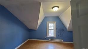 bonus room with hardwood / wood-style floors, lofted ceiling, and a baseboard heating unit