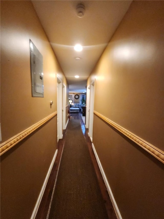 corridor with electric panel and dark carpet