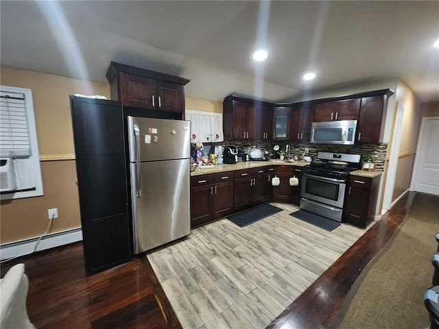 kitchen featuring dark brown cabinets, light wood-type flooring, appliances with stainless steel finishes, and tasteful backsplash