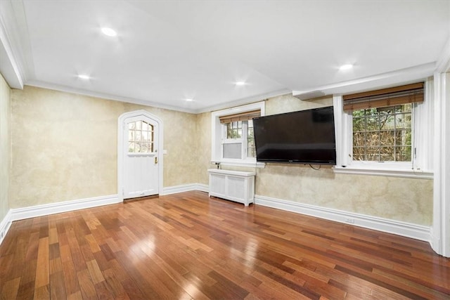 unfurnished living room with radiator heating unit, ornamental molding, plenty of natural light, and hardwood / wood-style flooring