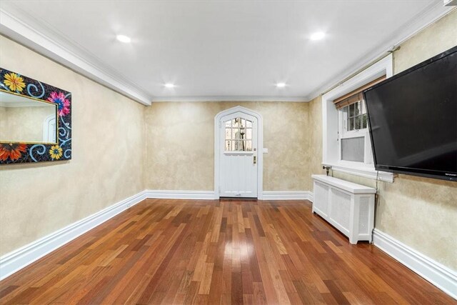 interior space with crown molding, a healthy amount of sunlight, and hardwood / wood-style flooring