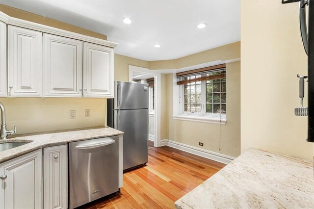 kitchen featuring white cabinets, light stone countertops, light wood-type flooring, and appliances with stainless steel finishes