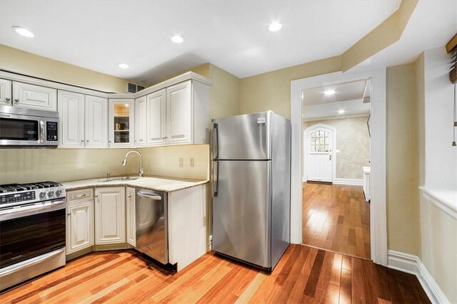 kitchen with white cabinets, sink, light wood-type flooring, and stainless steel appliances