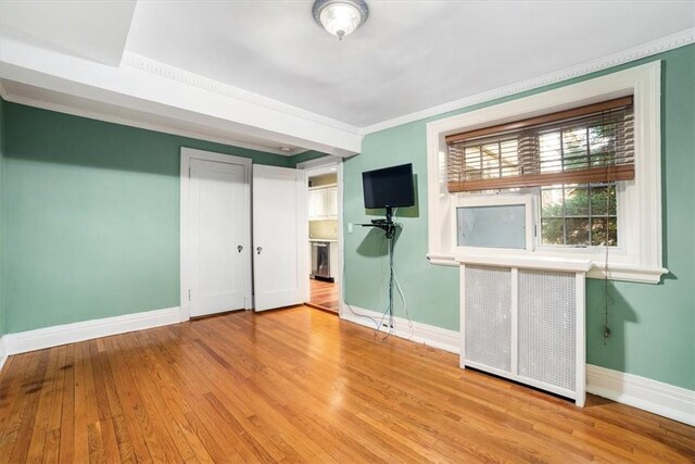 unfurnished bedroom featuring radiator heating unit, ornamental molding, and light hardwood / wood-style flooring