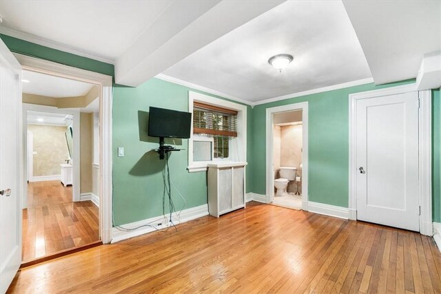 unfurnished bedroom featuring ensuite bathroom, crown molding, and light wood-type flooring