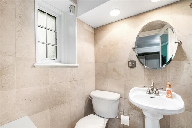 bathroom with sink, tile walls, and toilet