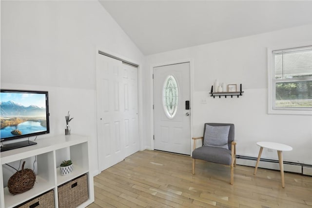 foyer with light hardwood / wood-style floors, vaulted ceiling, and a baseboard radiator