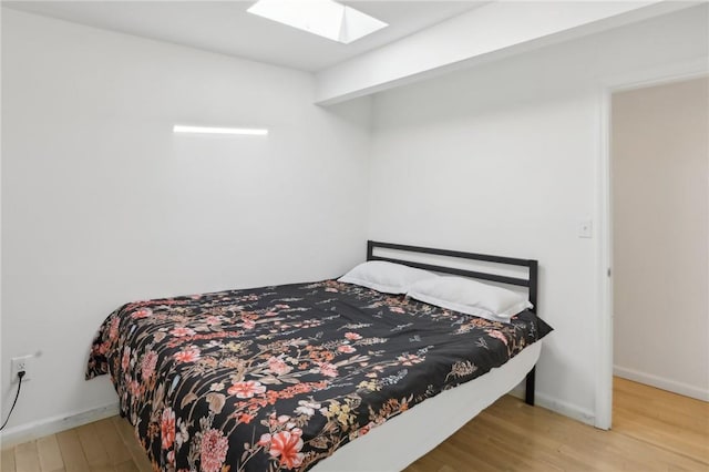 bedroom with wood-type flooring and a skylight