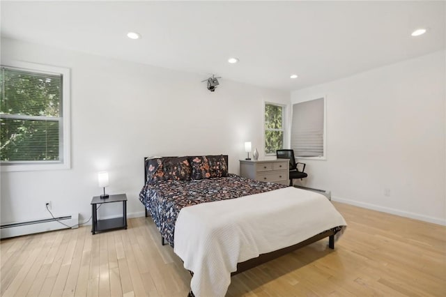 bedroom with light wood-type flooring and a baseboard heating unit