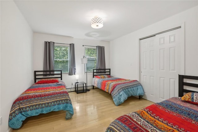 bedroom featuring hardwood / wood-style floors, a baseboard radiator, and a closet