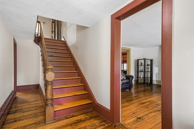 stairs featuring wood-type flooring and a baseboard radiator