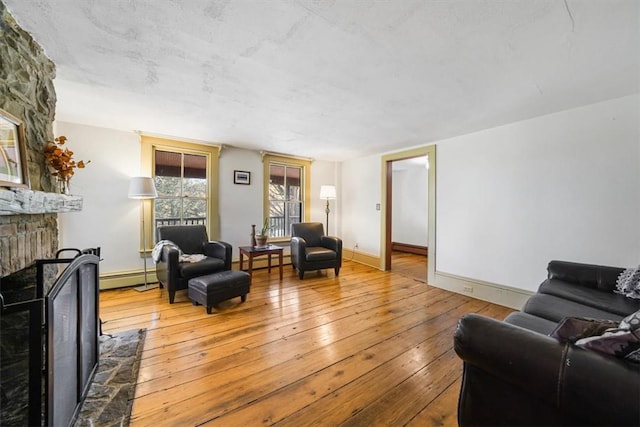 living room featuring baseboard heating, a fireplace, and wood-type flooring