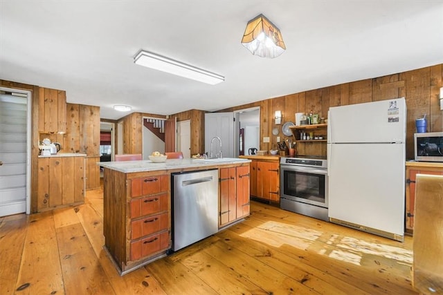 kitchen featuring sink, stainless steel appliances, light hardwood / wood-style floors, and an island with sink