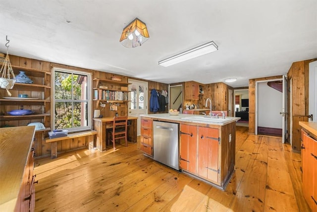 kitchen featuring dishwasher, light hardwood / wood-style floors, sink, and wooden walls