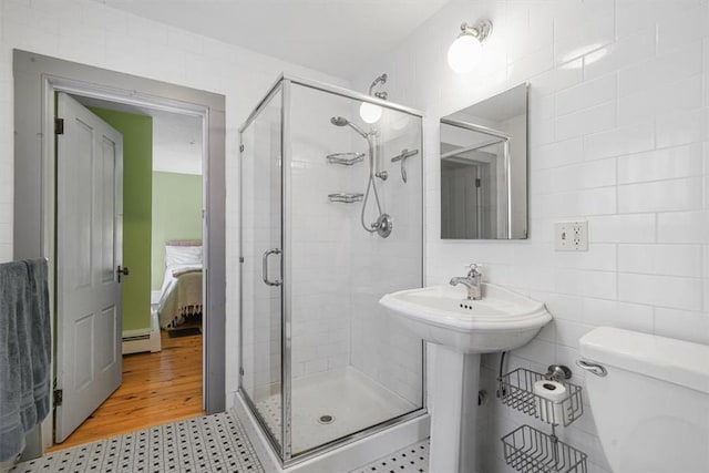 bathroom featuring walk in shower, hardwood / wood-style floors, a baseboard radiator, and tile walls