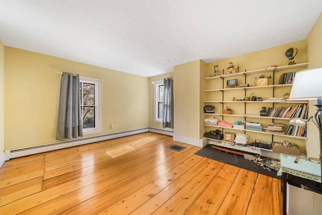 empty room with a baseboard radiator and light hardwood / wood-style flooring