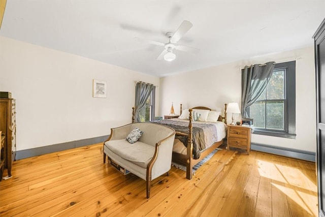 bedroom featuring light wood-type flooring, ceiling fan, and a baseboard heating unit