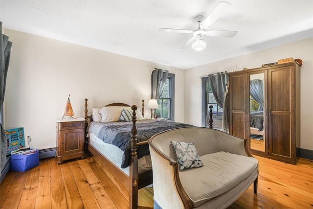 bedroom with ceiling fan, a baseboard heating unit, and light wood-type flooring