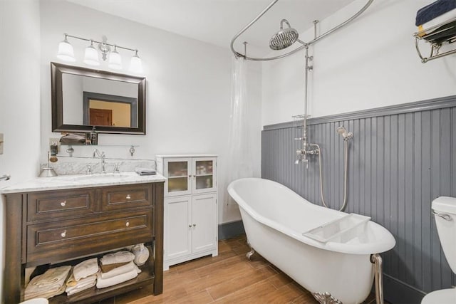 bathroom with a washtub, vanity, wood-type flooring, and toilet