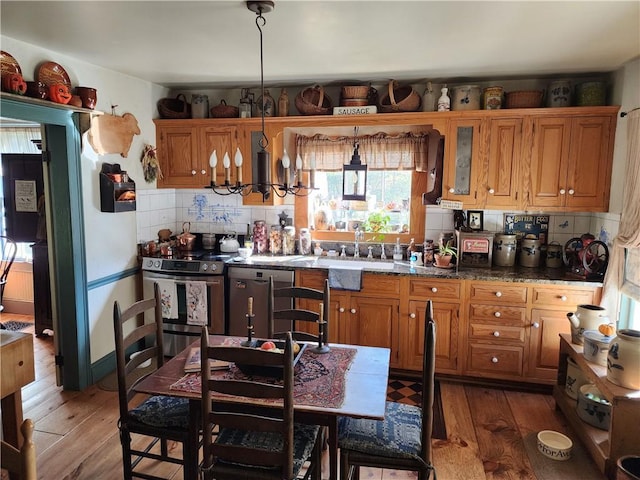 kitchen featuring pendant lighting, dark stone countertops, hardwood / wood-style floors, and appliances with stainless steel finishes