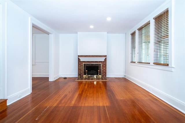 unfurnished living room featuring hardwood / wood-style floors and a brick fireplace