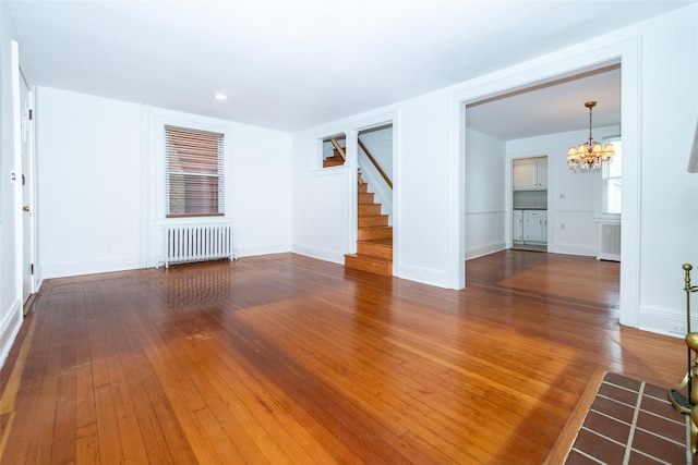 unfurnished living room featuring radiator heating unit, dark wood-type flooring, and an inviting chandelier