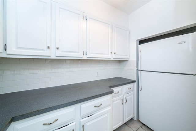 kitchen with light tile patterned floors, backsplash, white fridge, and white cabinetry