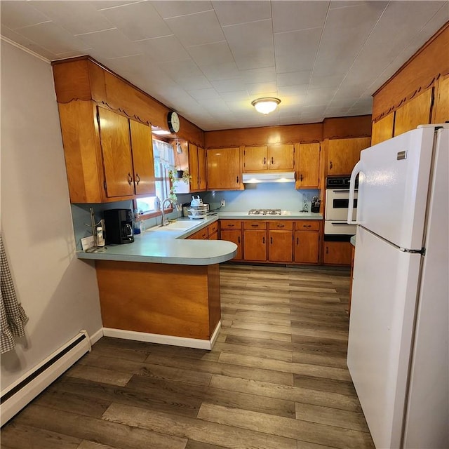 kitchen featuring hardwood / wood-style floors, white appliances, a baseboard radiator, and sink