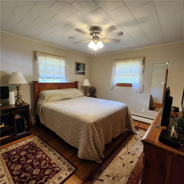 bedroom featuring baseboard heating, ceiling fan, wood-type flooring, and ornamental molding