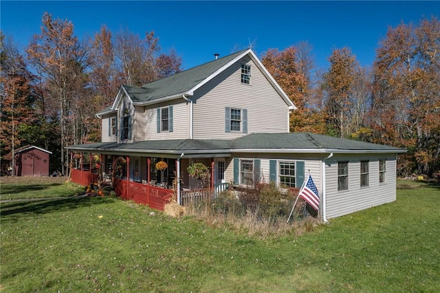 rear view of property featuring a lawn, a storage unit, and covered porch