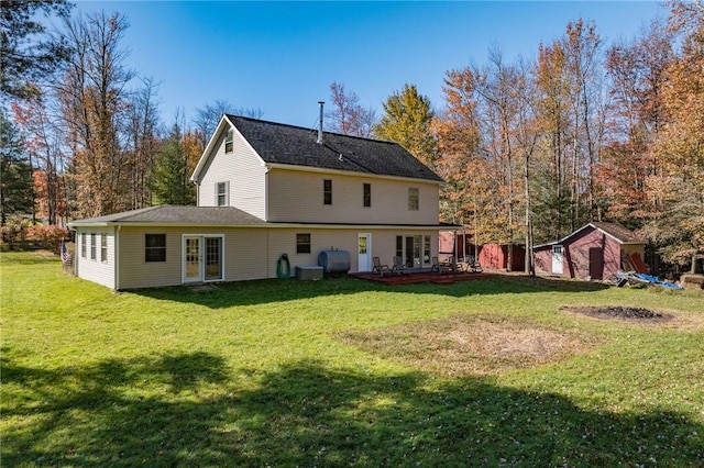 rear view of house featuring a yard, a deck, and a storage unit