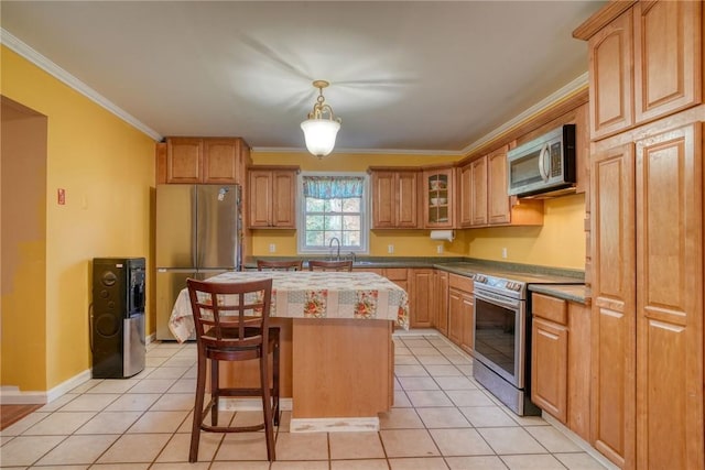 kitchen with appliances with stainless steel finishes, light tile patterned floors, a kitchen island, and ornamental molding